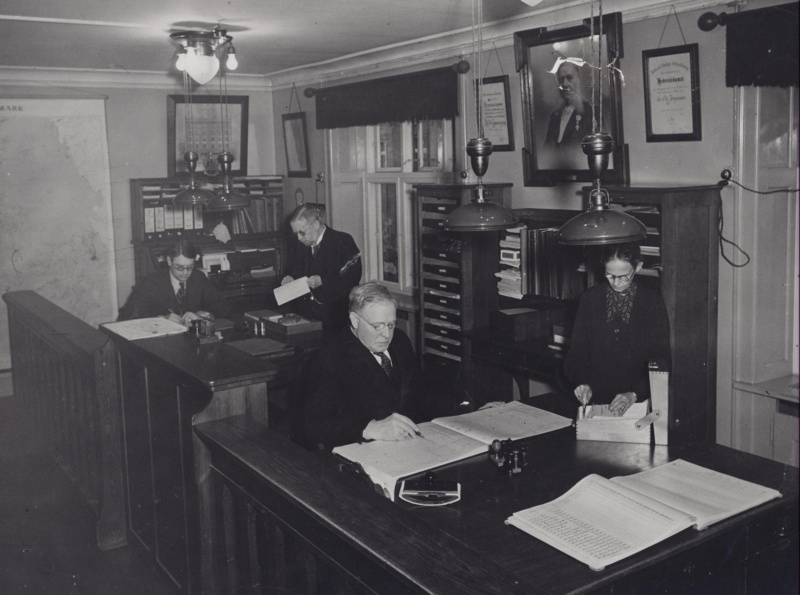 1935 4 særdeles flittige mennesker på 1866s kontor. På væggen holder Ole Jørgensen et vågent øje med Charles Behrendt, Carl Becker, Georg Rasmussen og Margrethe Becker.
