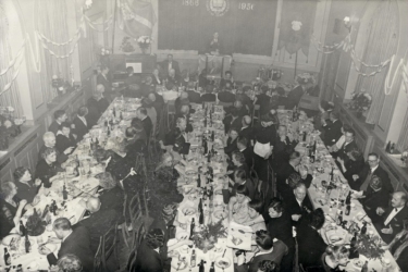 1956 Døveforeningen af 1866 holder 90 års jubilæumsfest i Brohusgade med smørrebrød, øl og en lille skarp. Pastor Behrendt holder jubilæumstalen fra talerstolen, der er prydet med et maleri af foreningens stifter, Ole Jørgensen.