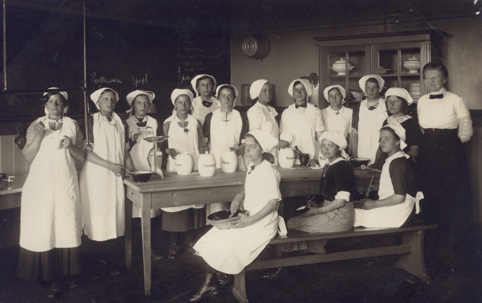 1905 Behovet for at lære pigerne at håndtere køkkengrejet fik forstander Forchhammer til at inddrage en læseklasse til skolekøkken, hvor frk. M. Andersen kunne lære pigerne at kokkerere.