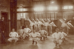 1916 Kaptajn Rasmussen dirigerer gymnastikken med en stok i hånden, som kunne bruges, hvis nogen ikke helt fulgte instrukserne.