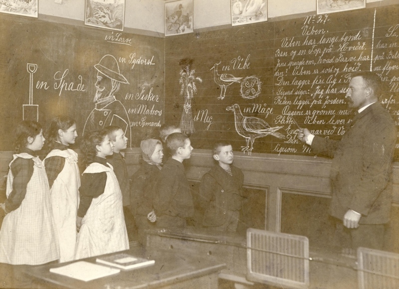 1907 Korlæsning efter Mund-Haandsystem. Indøvelse af MHS kunne også ske ved korlæsning. Det kan ikke have været helt nemt for eleverne, både at følge det skrevne ord på tavlen og lærerens mund og hånd