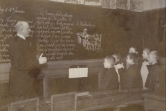 1907 Korlæsning fra Tavle. Hænderne på ryggen, så man ikke skulle fristes til at snakke med og derved forstyrre oplæsningen